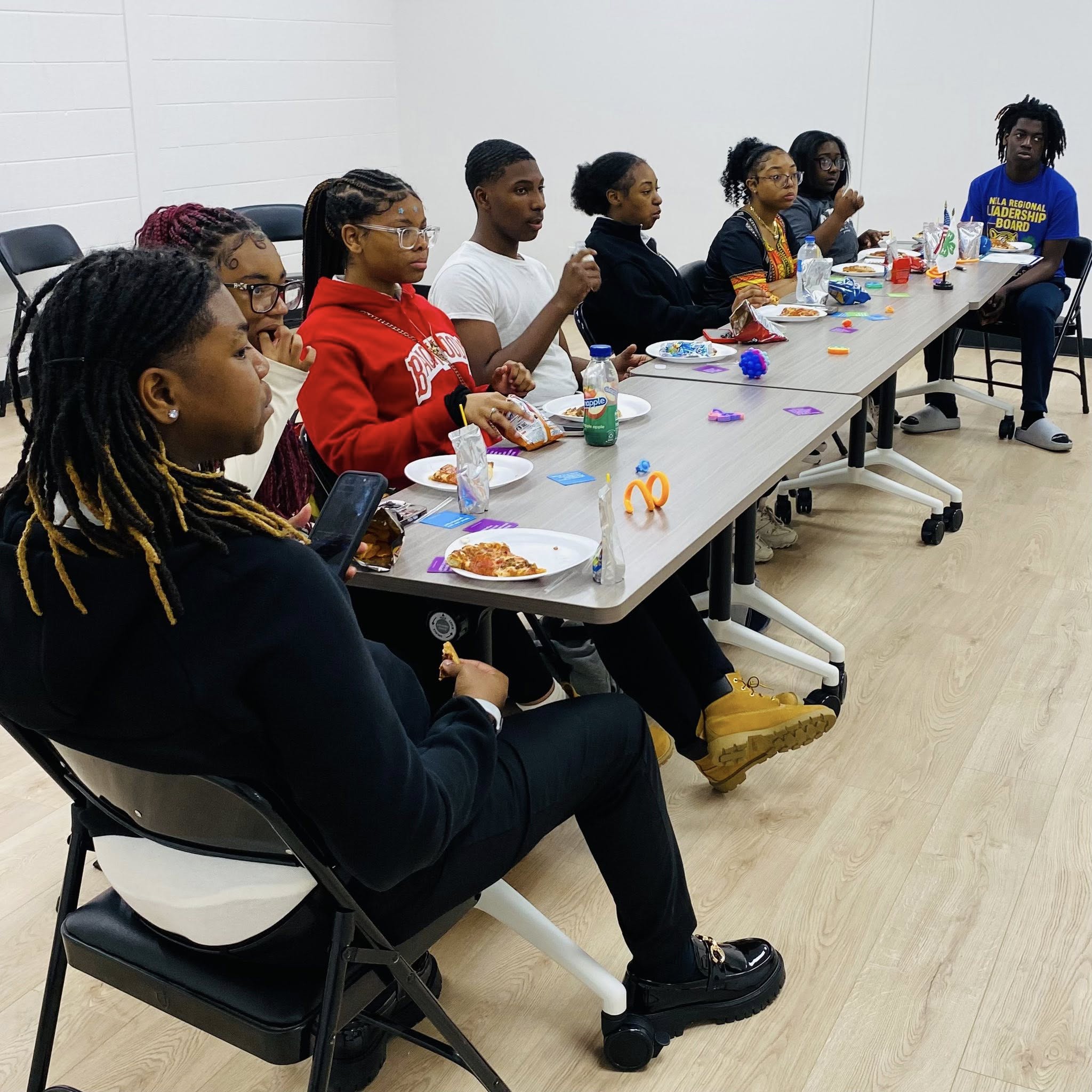 A group of teenagers sitting at a long table.